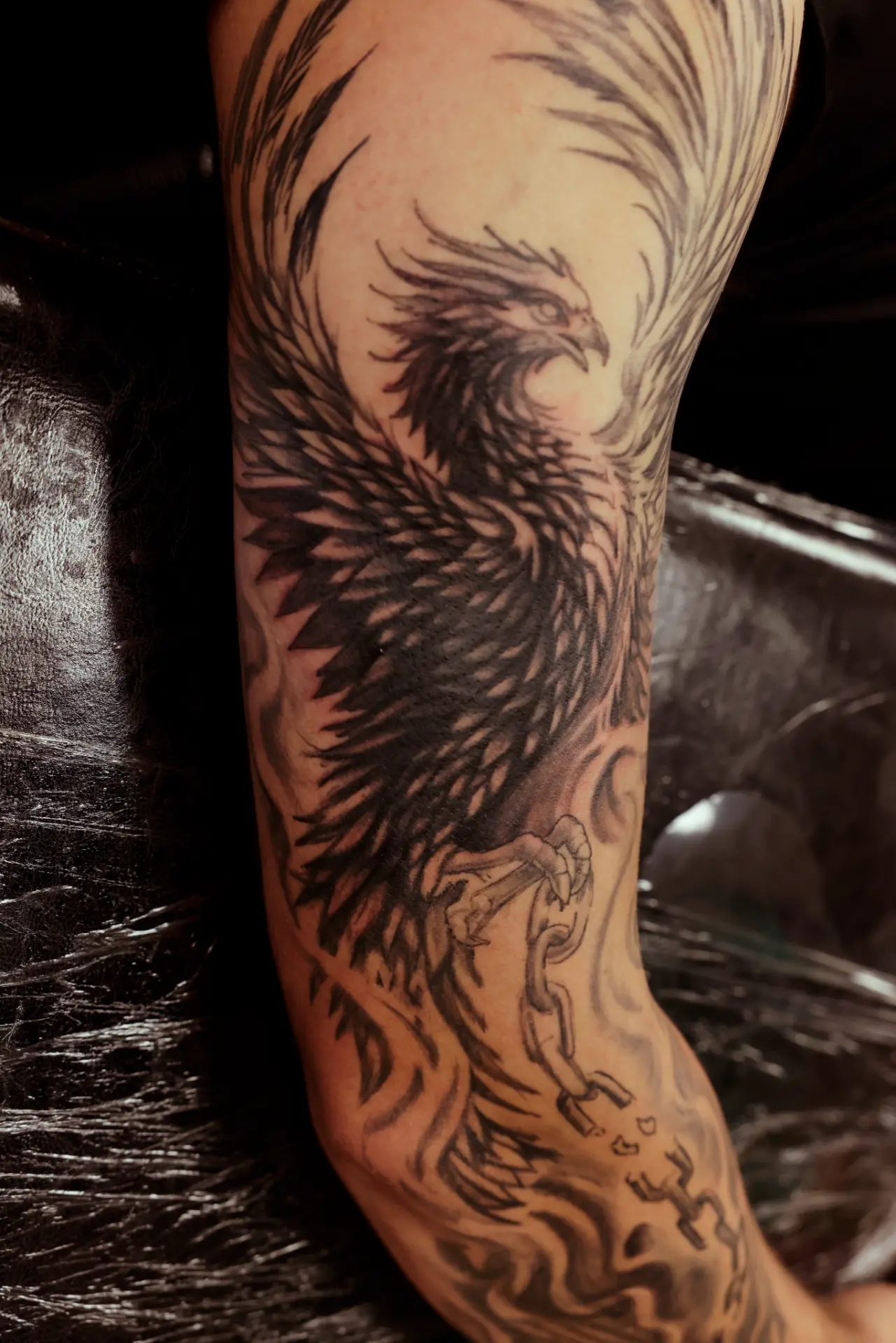 Black and grey realism eagle with broken chain tattoo on an arm