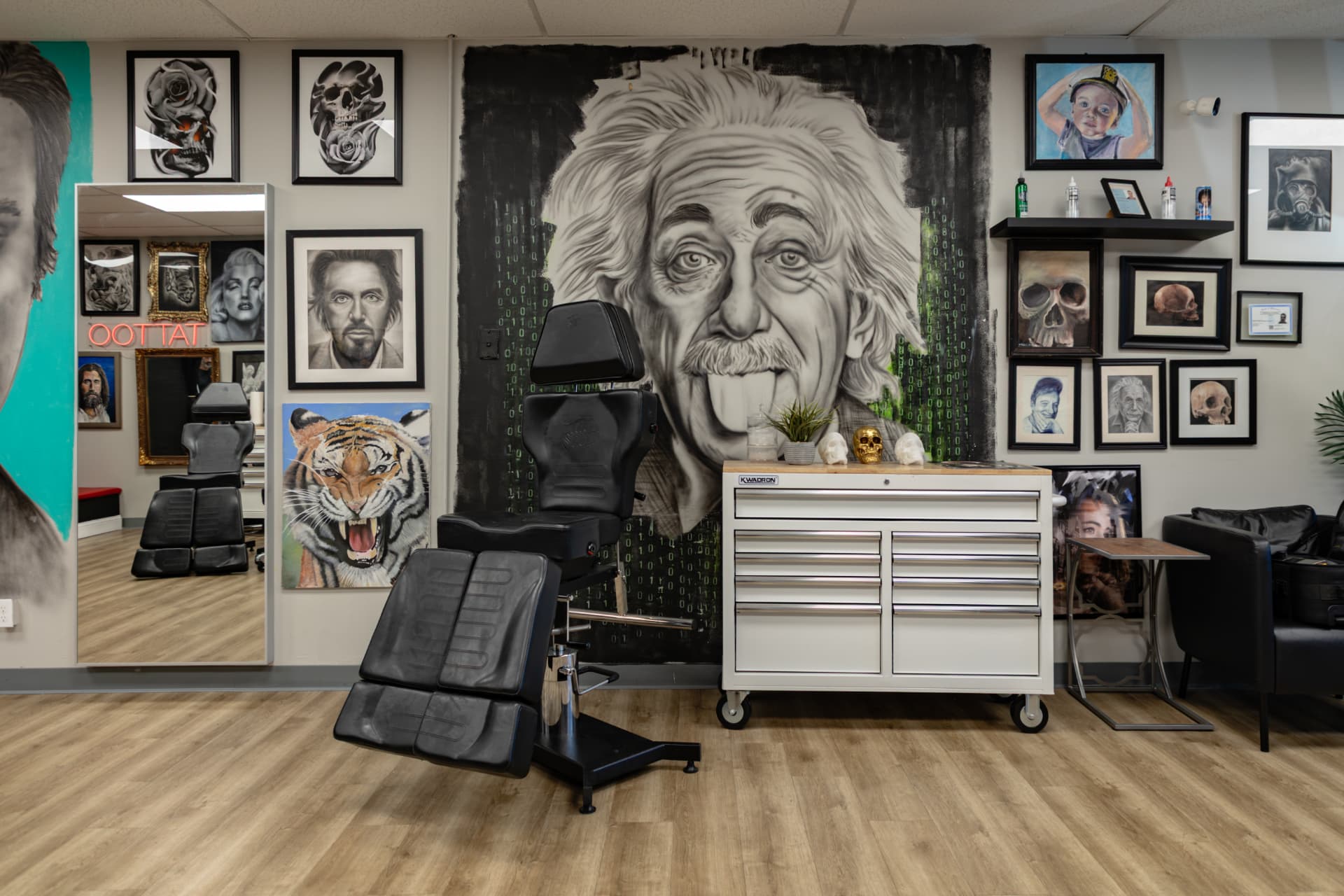Private tattoo booth at Crimson Dove Tattoo with a black leather chair, a white tool chest, and framed artwork