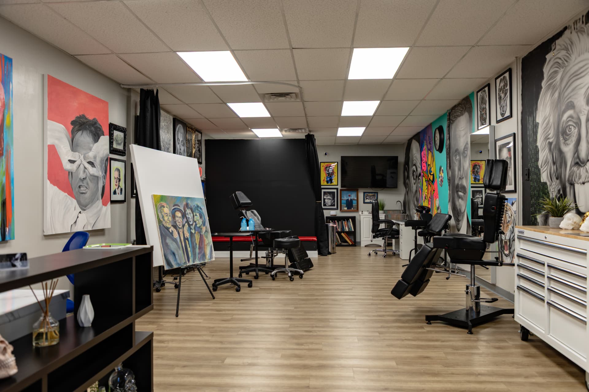 Open studio floor at Crimson Dove Tattoo with two black tattoo chairs, rolling tool carts, and large wall murals